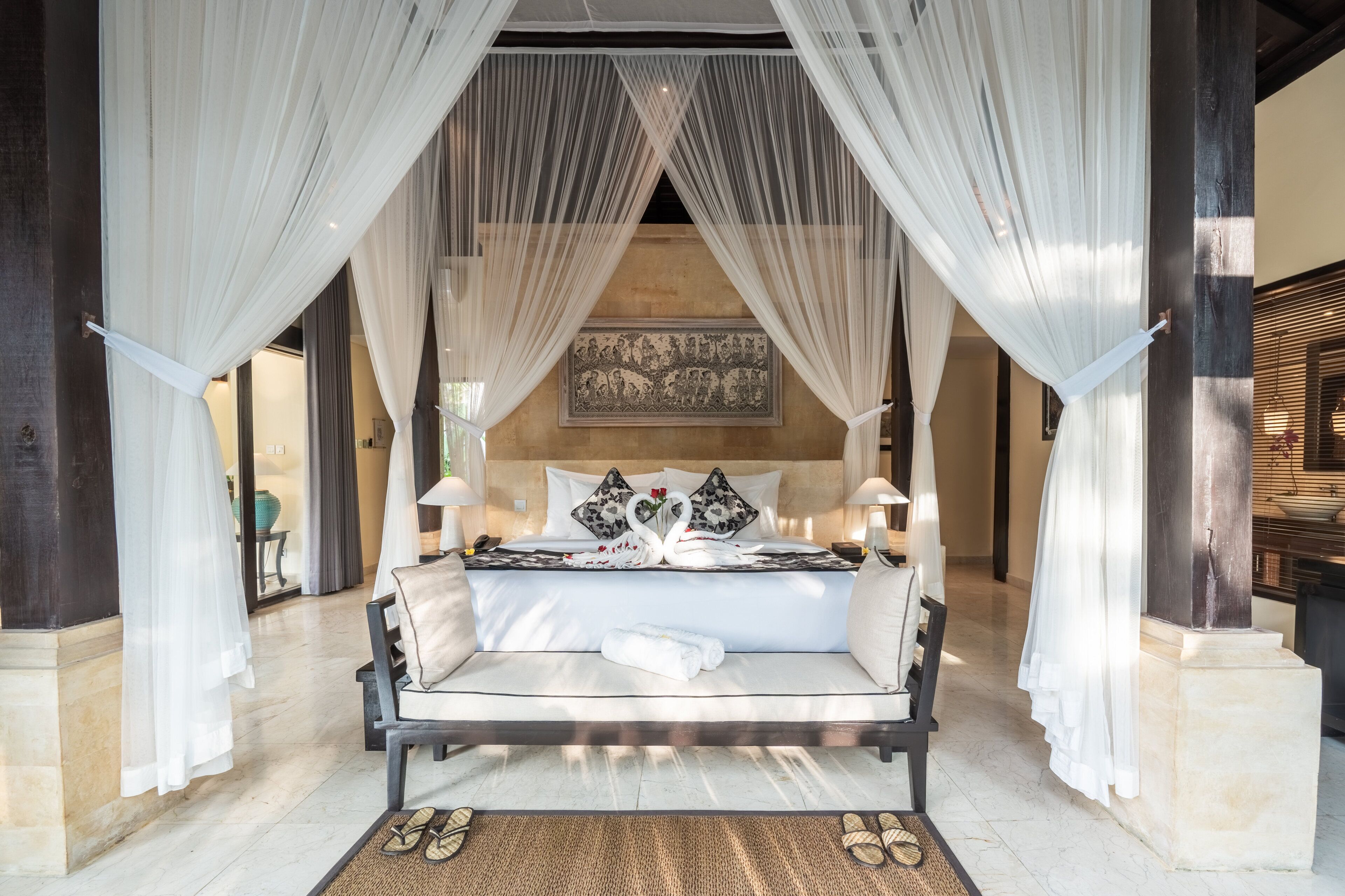 A bed with white linens, a canopy, and a wall-mounted artwork.