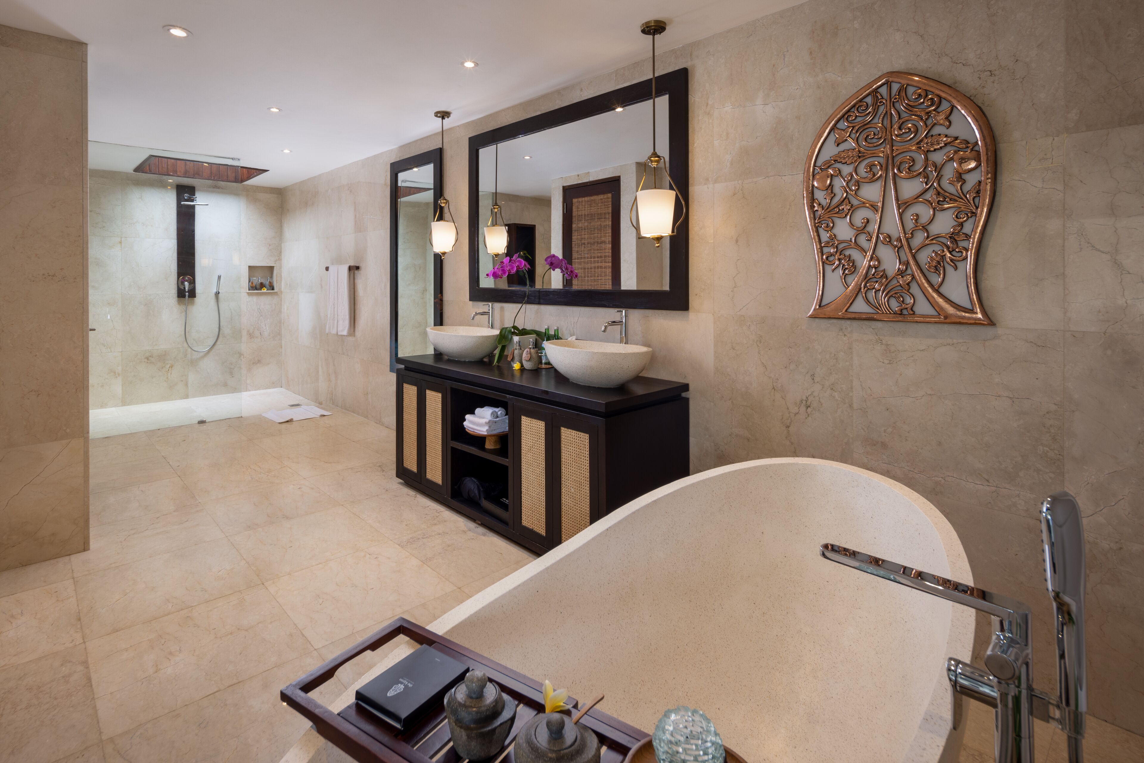 Un baño moderno con una bañera independiente, un espejo grande y un adorno de pared decorativo.