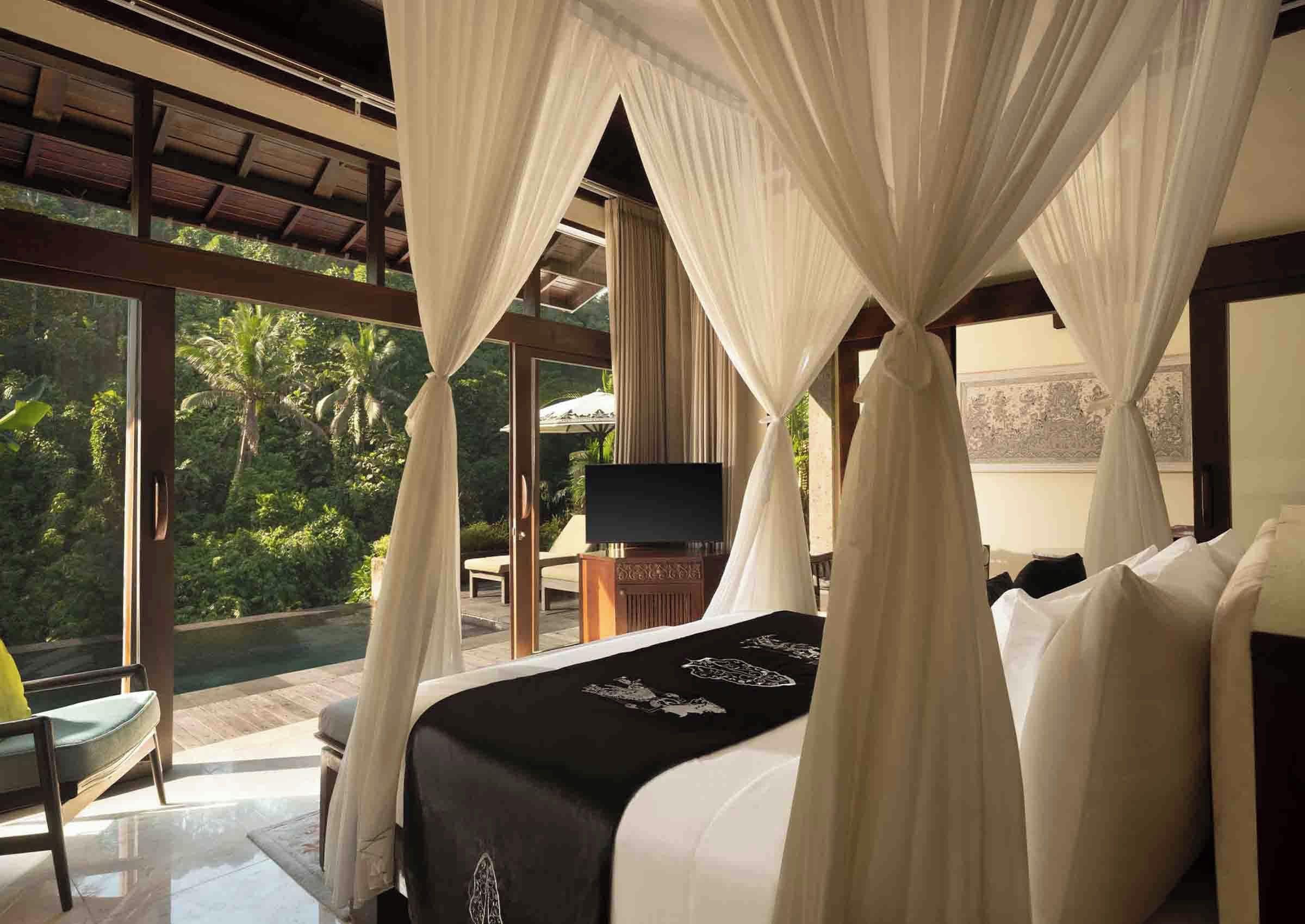 A bedroom with a canopy bed, a television, and a view of the outdoors.