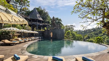 Una piscina al aire libre, sombrillas, sillones reclinables de piscina