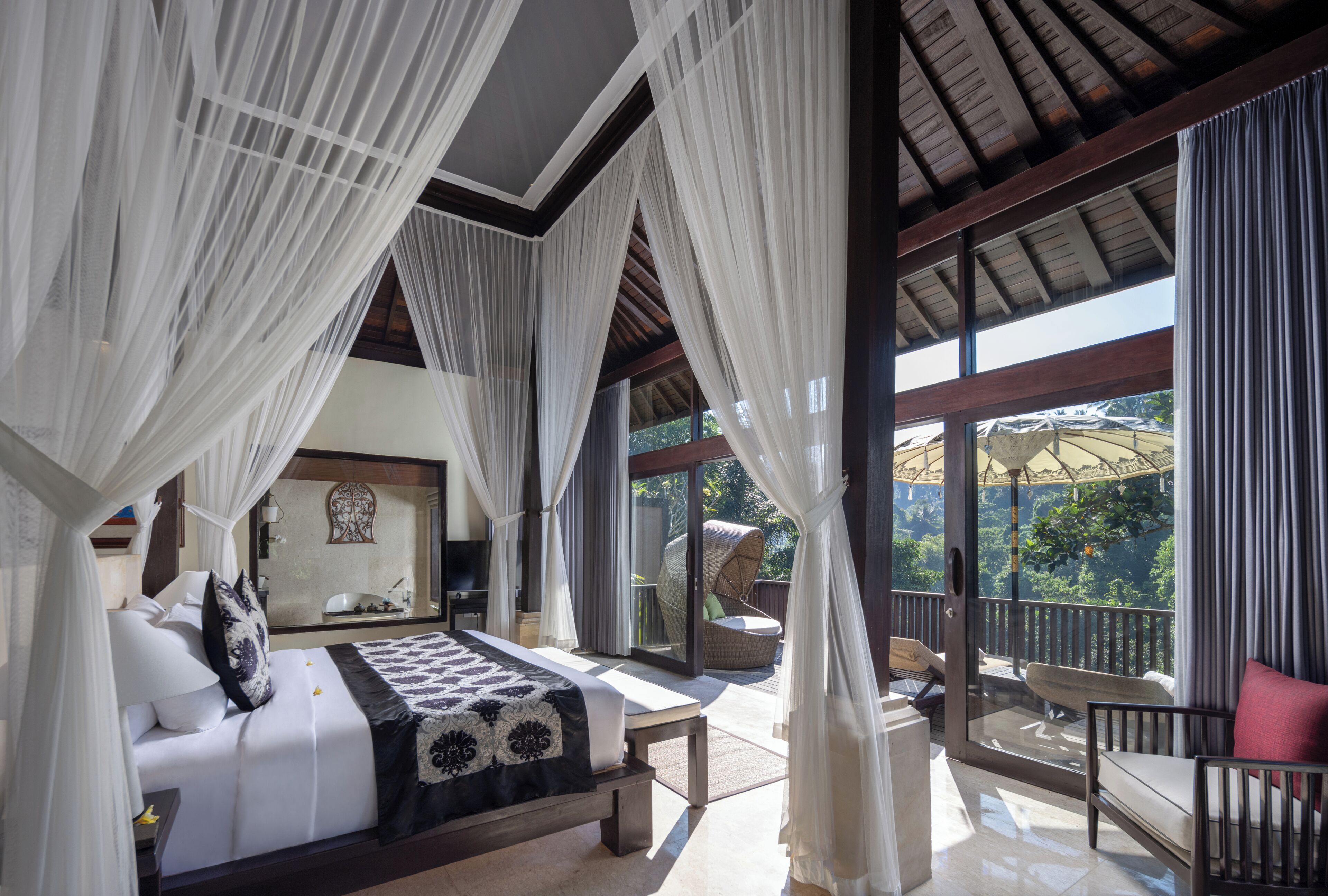 A bedroom with a bed, a balcony with a chair, and a view of the outdoors.