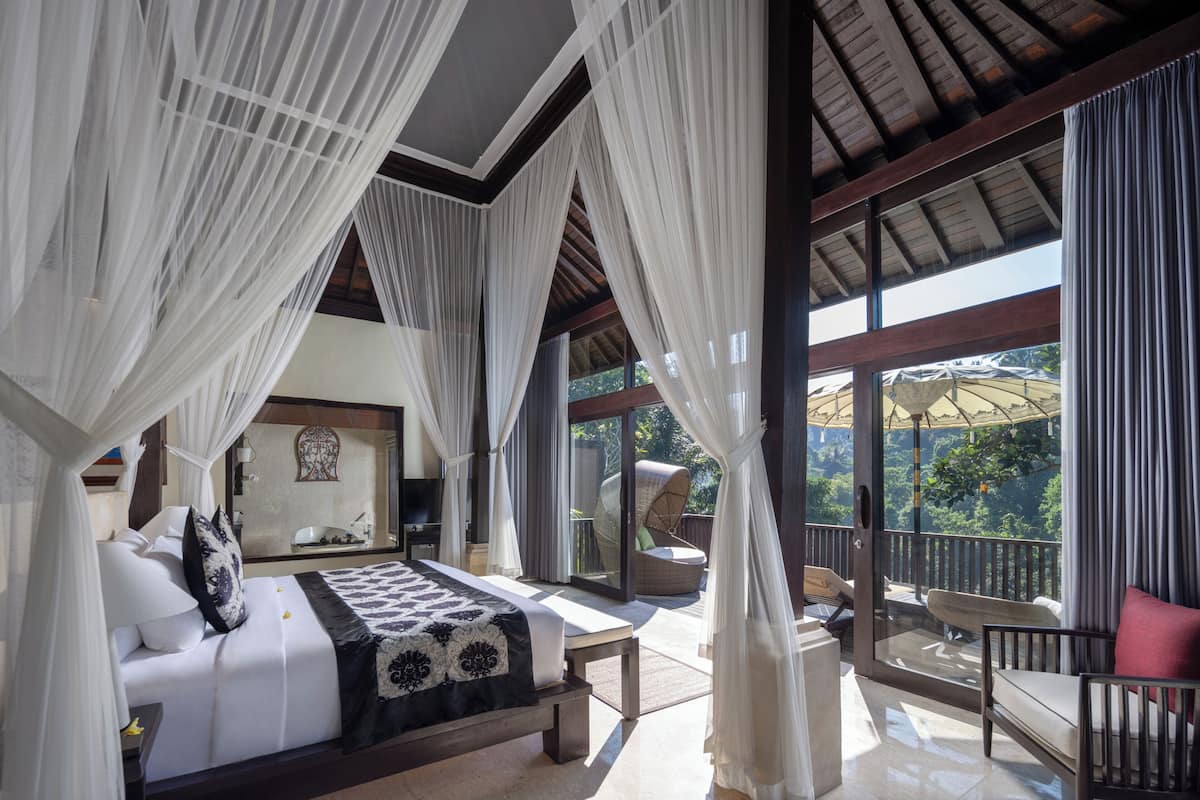 Un dormitorio con cama, un balcón con silla y vistas al exterior.