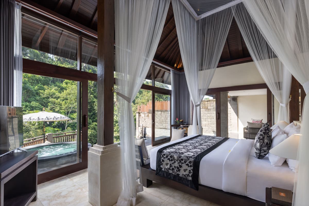 Un dormitorio con una cama grande, televisión y vistas a una piscina y jardín.