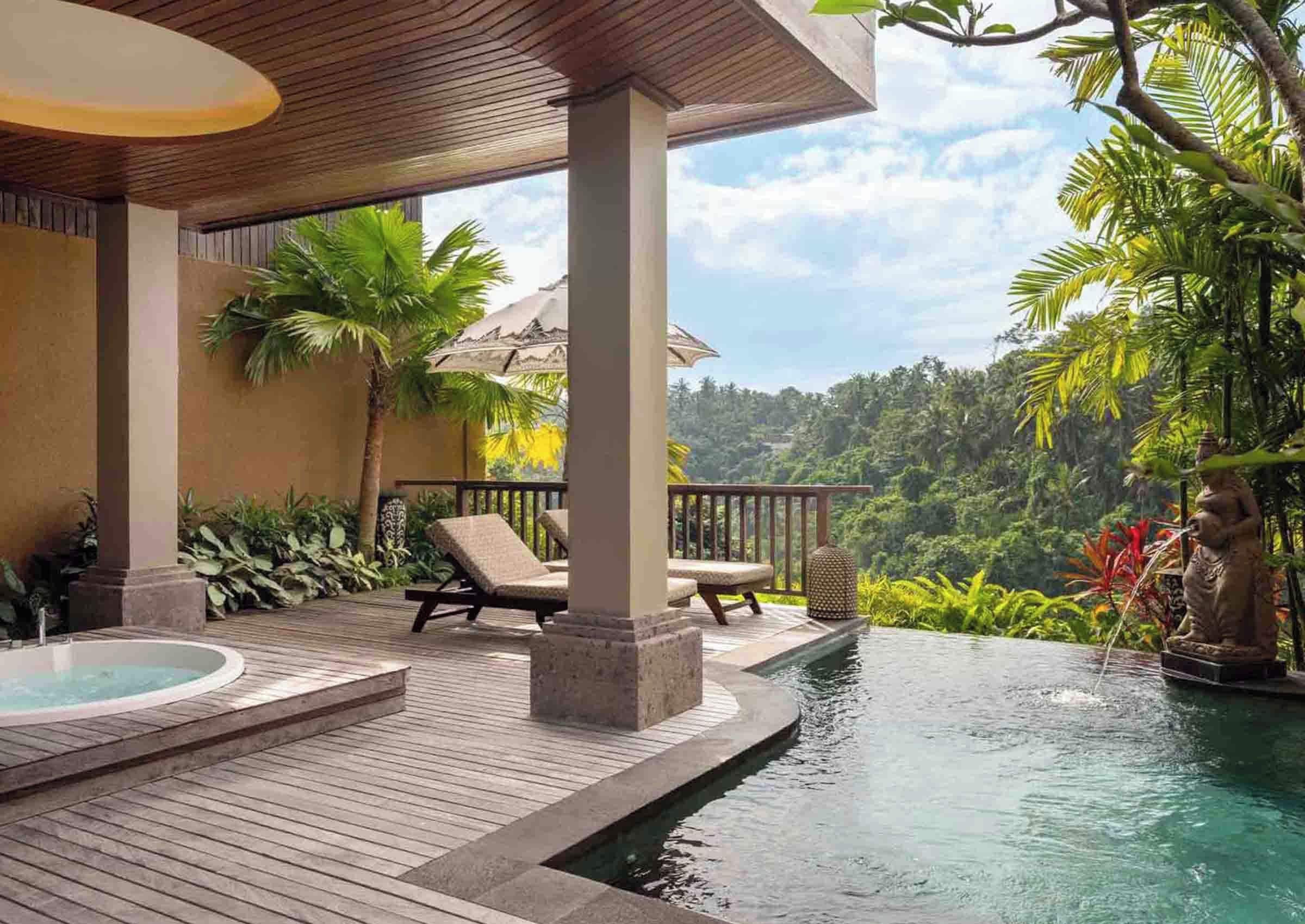A wooden deck with a hot tub, lounge chairs, and a pool with a statue.