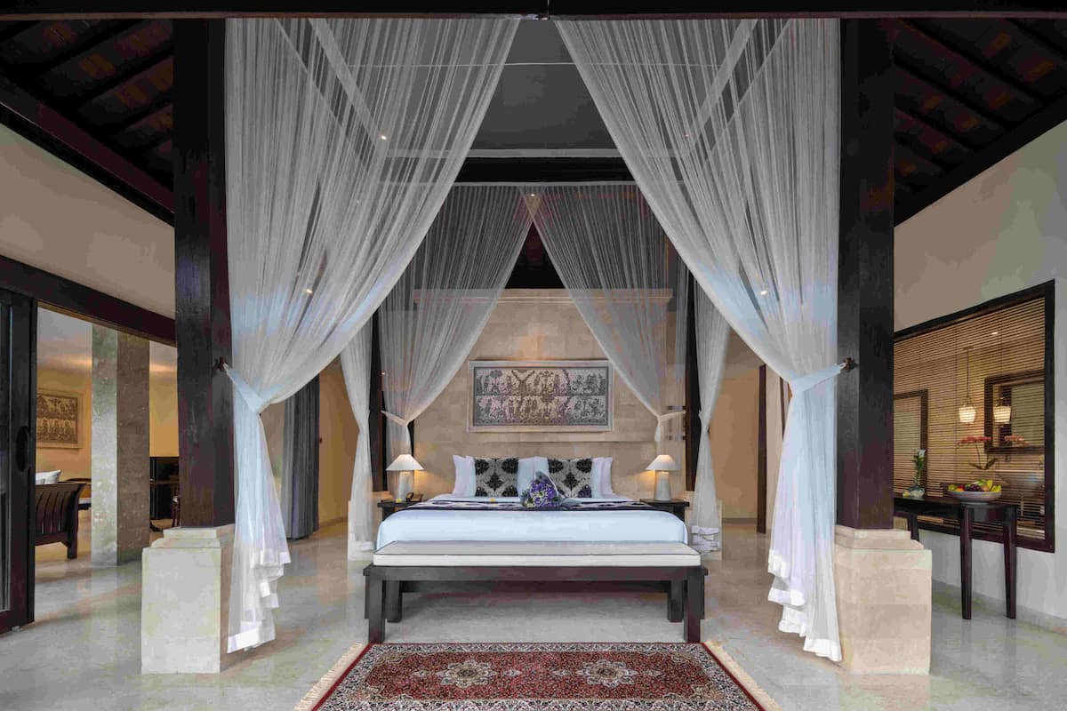 Un dormitorio amplio con una cama grande, un tapete decorativo y cortinas traslúcidas.