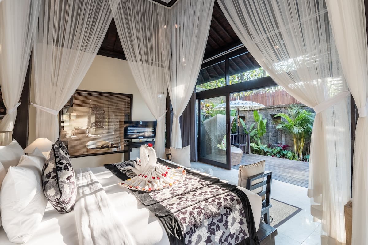 Un dormitorio amplio con una cama grande, televisor y vista al jardín exterior.