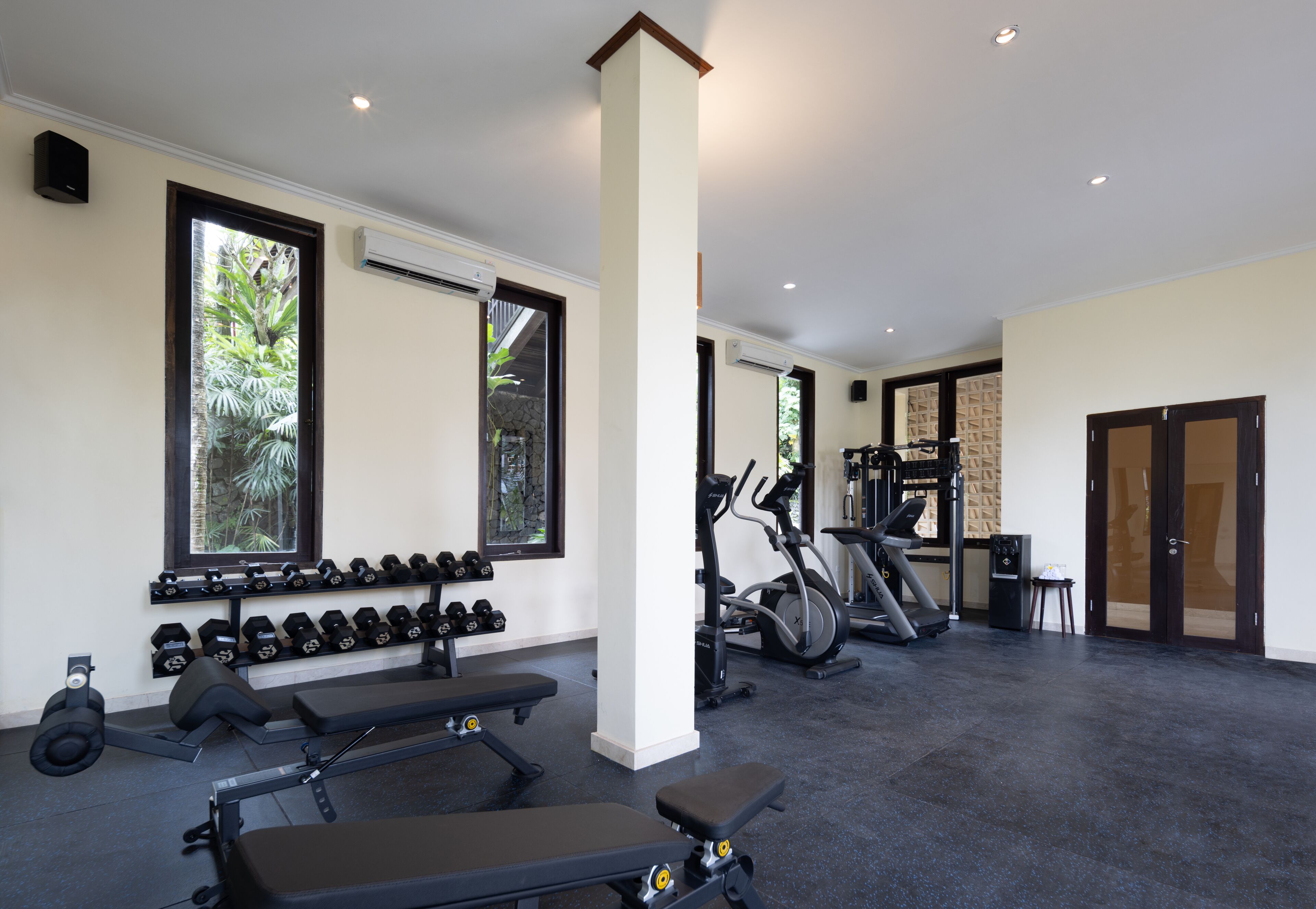 Un gimnasio con equipo de ejercicio, mancuernas, cintas de correr y bicicletas estáticas.