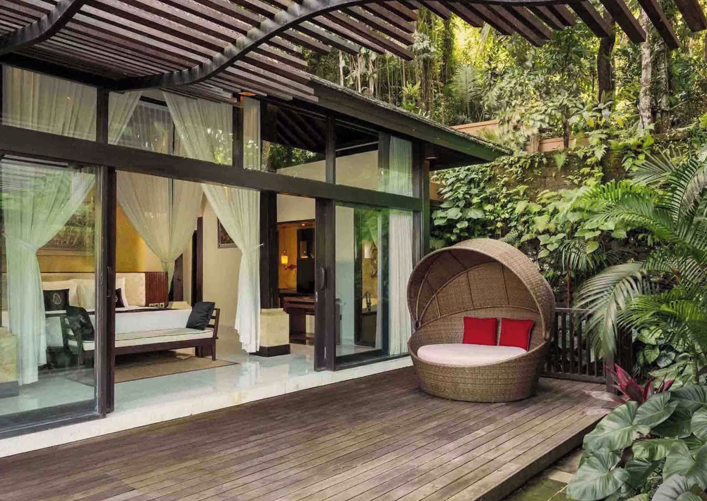 A modern villa with a glass-enclosed bedroom, a wooden deck, and a hanging chair.