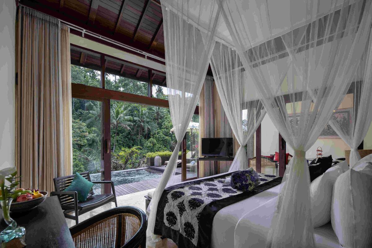 Un dormitorio con un ventanal grande, una cama con dosel, un televisor y vistas al exterior.