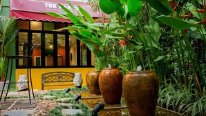 An outdoor seating area with a yellow bench, large vases, and a water feature. - Tee Pak Dee Resident Phuket (Phuket)