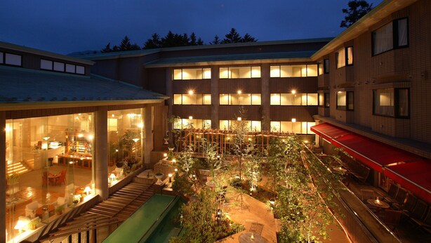 A hotel courtyard with indoor seating, a green water feature, and multiple levels of balconies. - Hotel Cypress Karuizawa (Karuizawa)