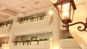 A multi-level interior with balconies adorned with greenery, a classic lantern-style light fixture, and a clean, white color scheme. - Hotel Cypress Karuizawa (Karuizawa)