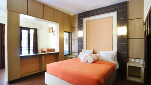 A modern hotel room with a large bed, wooden paneling, a built-in desk, and a large mirror.