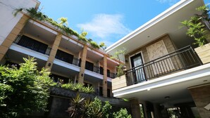 A multi-story building with balconies, some with plants.