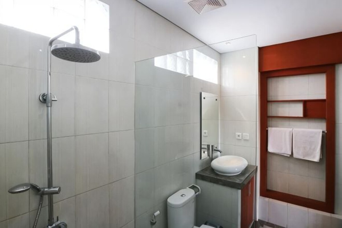 A modern bathroom with a glass shower enclosure, a white sink, and a mirror above the sink.