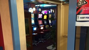 An entrance to a gaming area with slot machines and a neon sign. - Beach Hotel (Burnie)
