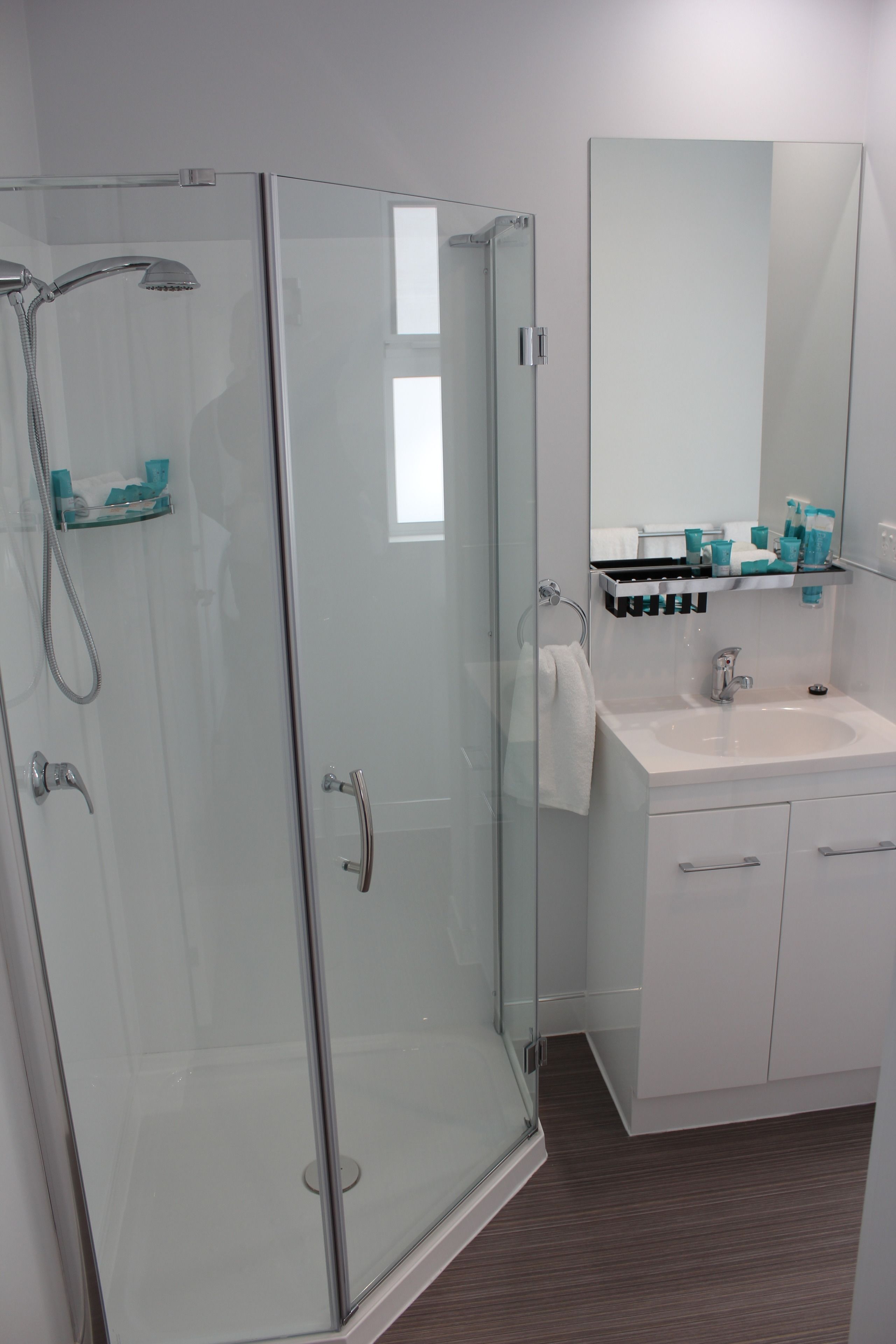 A modern bathroom with a glass-enclosed shower, a white sink, and a mirror above it.