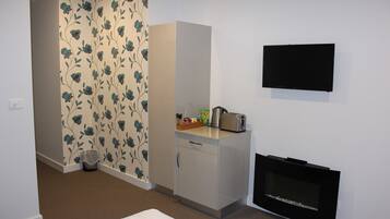 Una habitación con kitchenette, televisor de pantalla plana montado en la pared y papel tapiz estampado.