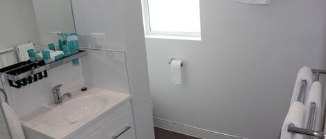 A modern bathroom with a white sink, mirror, and towel rack.