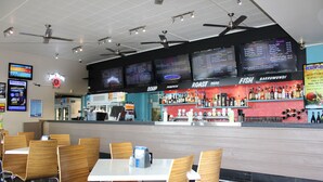 A restaurant with multiple menu boards, a bar area, and seating for diners. - Beach Hotel (Burnie)