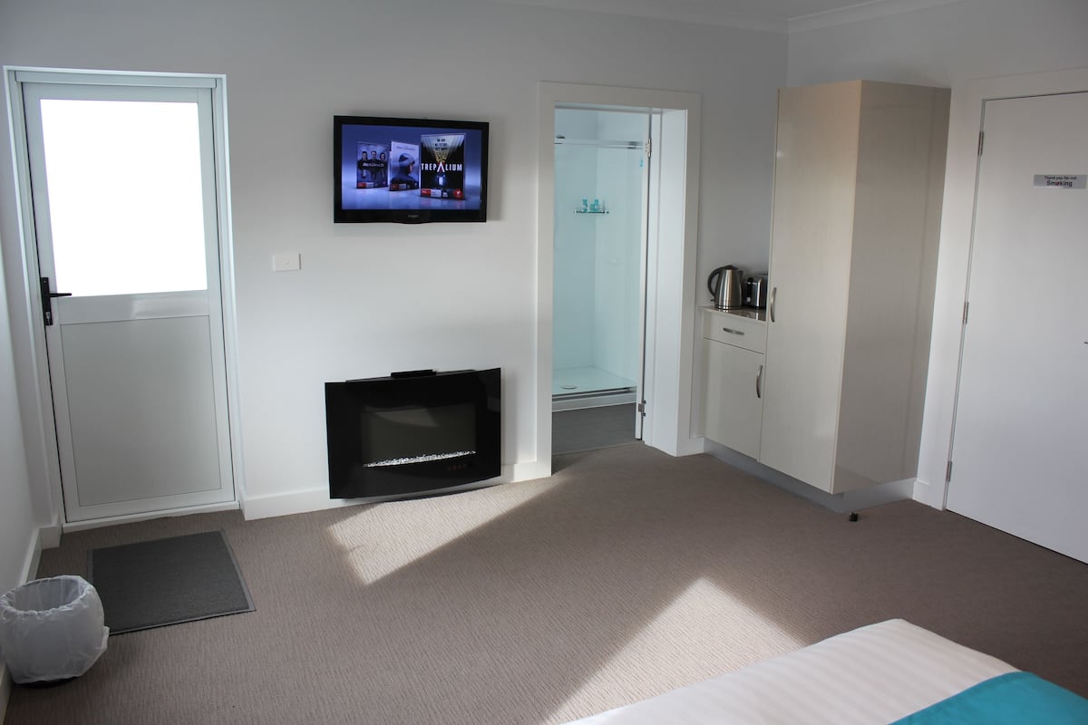 Ein Hotelzimmer mit Bett, Fernseher, Kleiderschrank und Duschbereich.