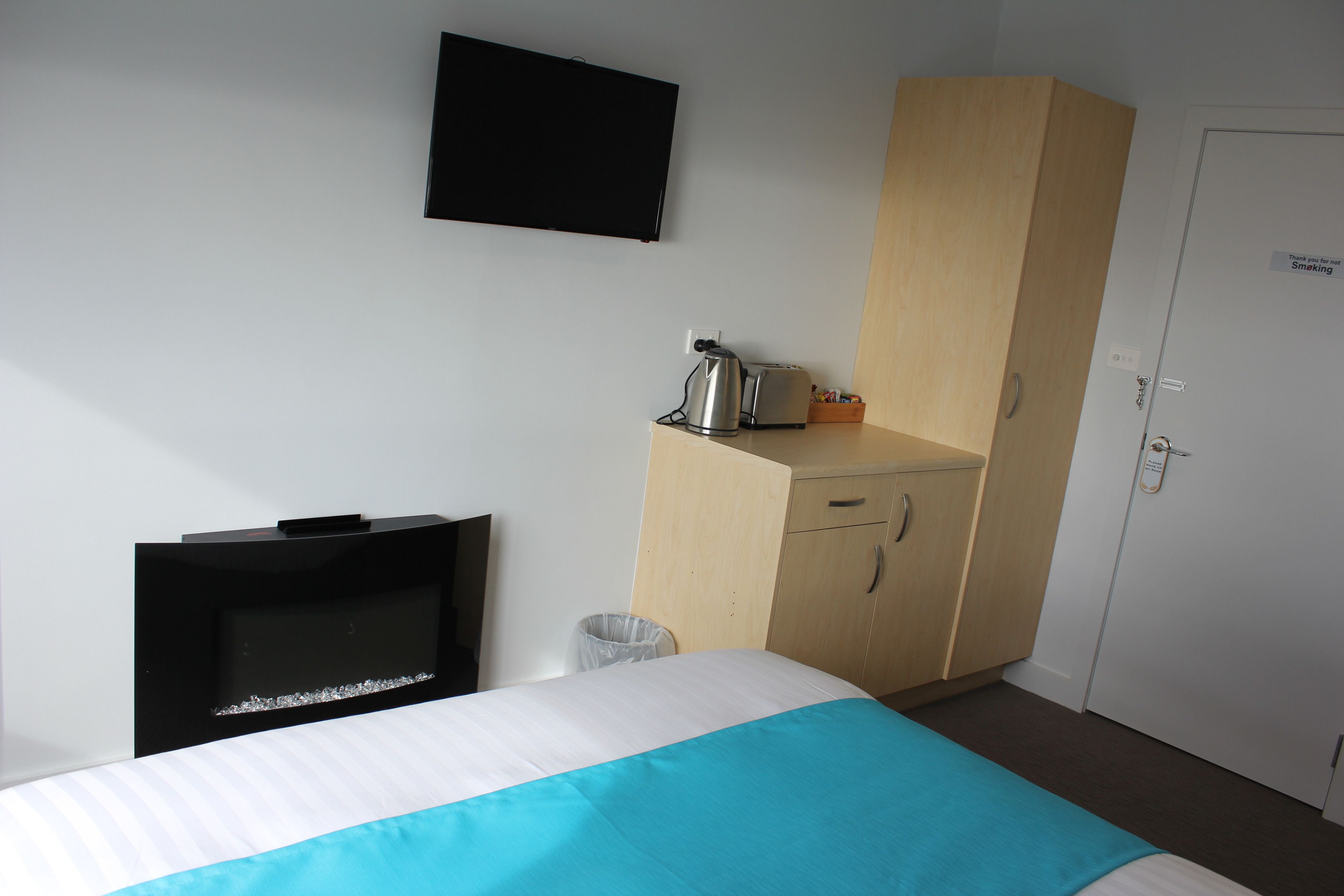 Una camera d'albergo con un letto, una TV, angolo cottura e un armadio.