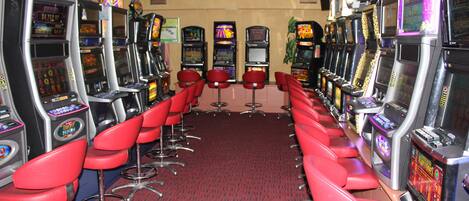 Eine Reihe Spielautomaten mit roten Sesseln dazwischen.