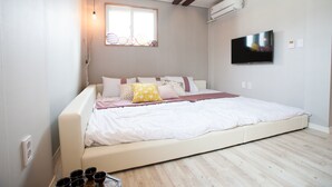 Un dormitorio moderno con una cama grande, televisión y ventana con vidrio decorativo.