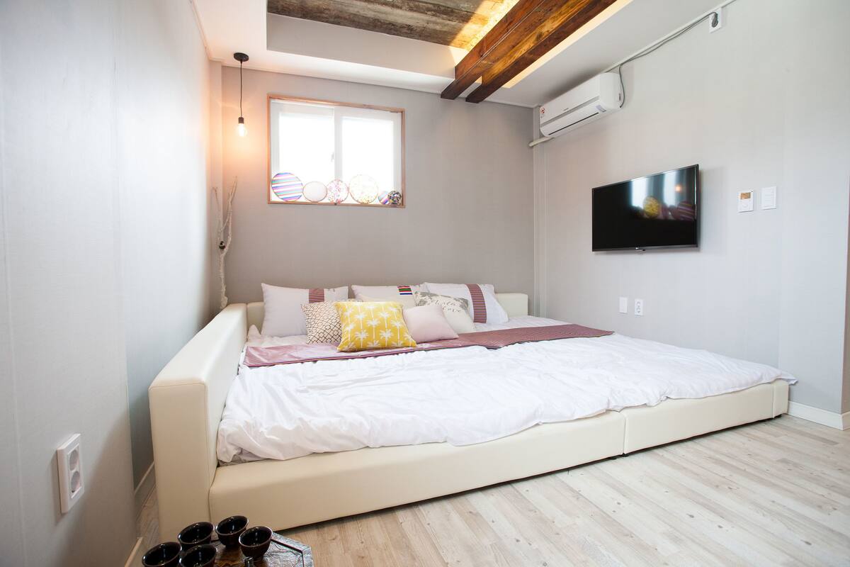 Une chambre moderne avec un grand lit, une télévision et une fenêtre ornée de vitraux.