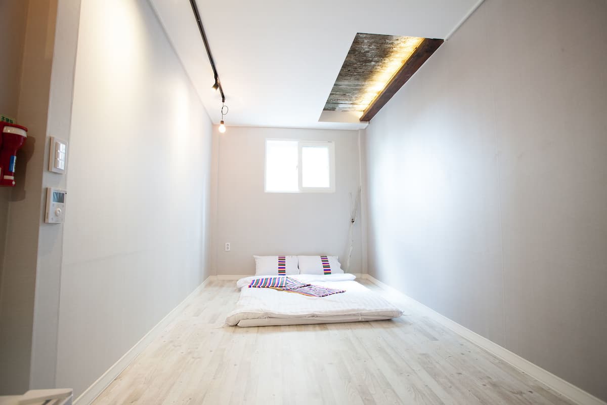 Une petite pièce lumineuse, avec un lit, une fenêtre et un plafond en pente.