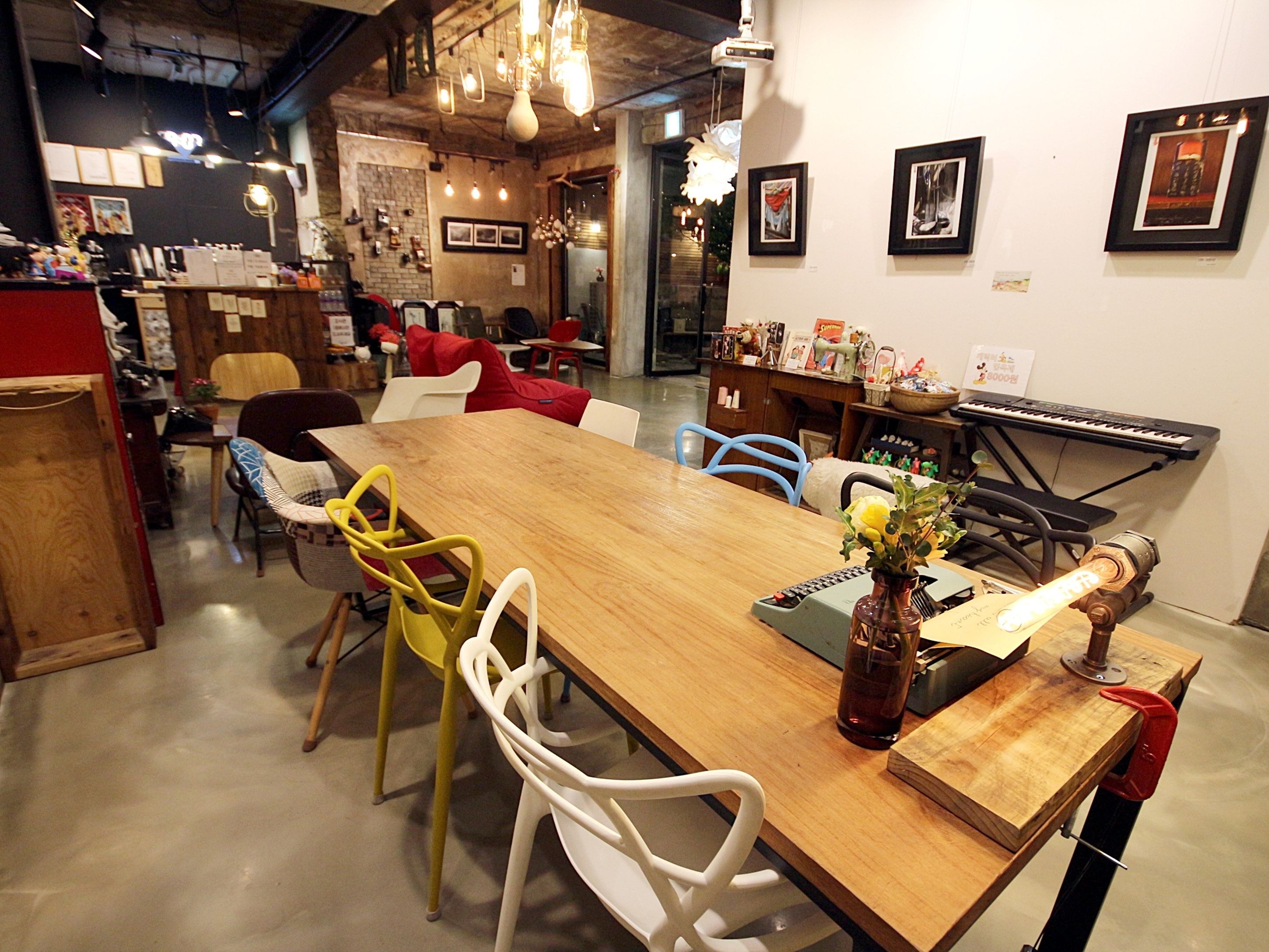 A dining area with a wooden table, colorful chairs, a vase with flowers, and a keyboard on a stand.