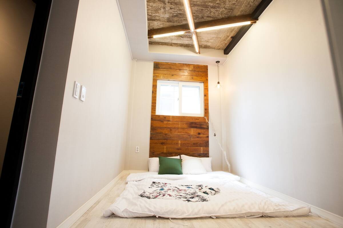 Une petite pièce avec un lit, un mur décoratif en bois et une fenêtre.