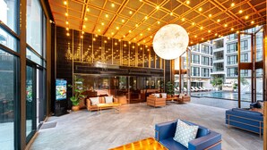 A modern lobby with a large pool, comfortable seating areas, and a ceiling with hanging lights. - Beston Pattaya (Pattaya)