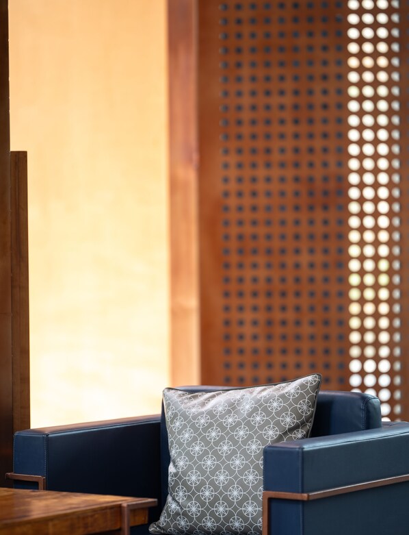 A modern lounge area with a blue sofa, a patterned pillow, and a wooden table. - Beston Pattaya (Pattaya)