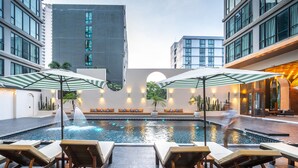 A rooftop pool area with lounge chairs and umbrellas, surrounded by modern buildings. - Beston Pattaya (Pattaya)
