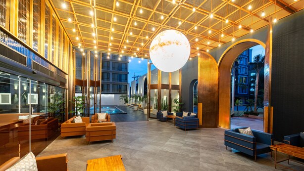 A spacious lobby with a high ceiling, modern furniture, and a large spherical light fixture. - Beston Pattaya (Pattaya)