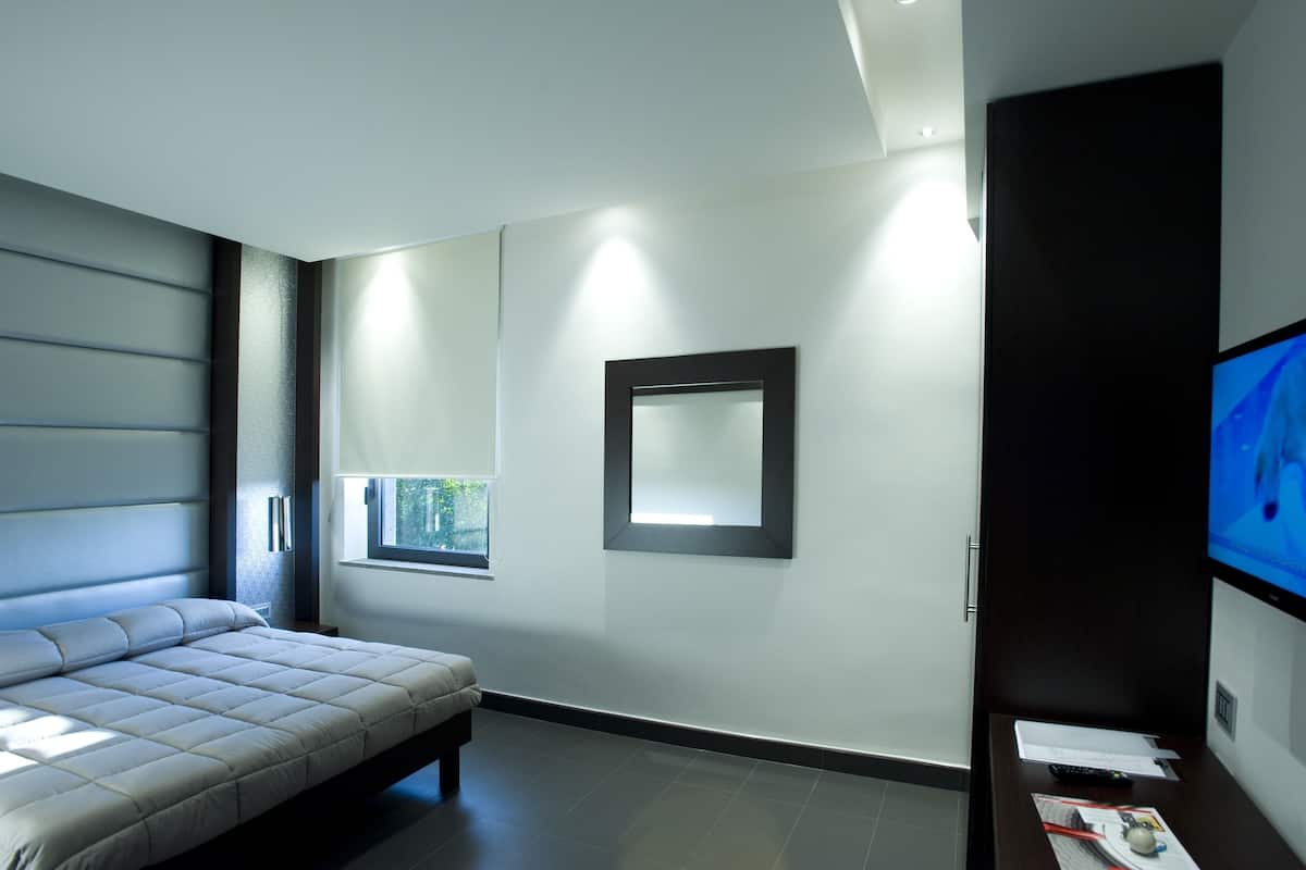 A modern bedroom with a bed, a TV, and a window.