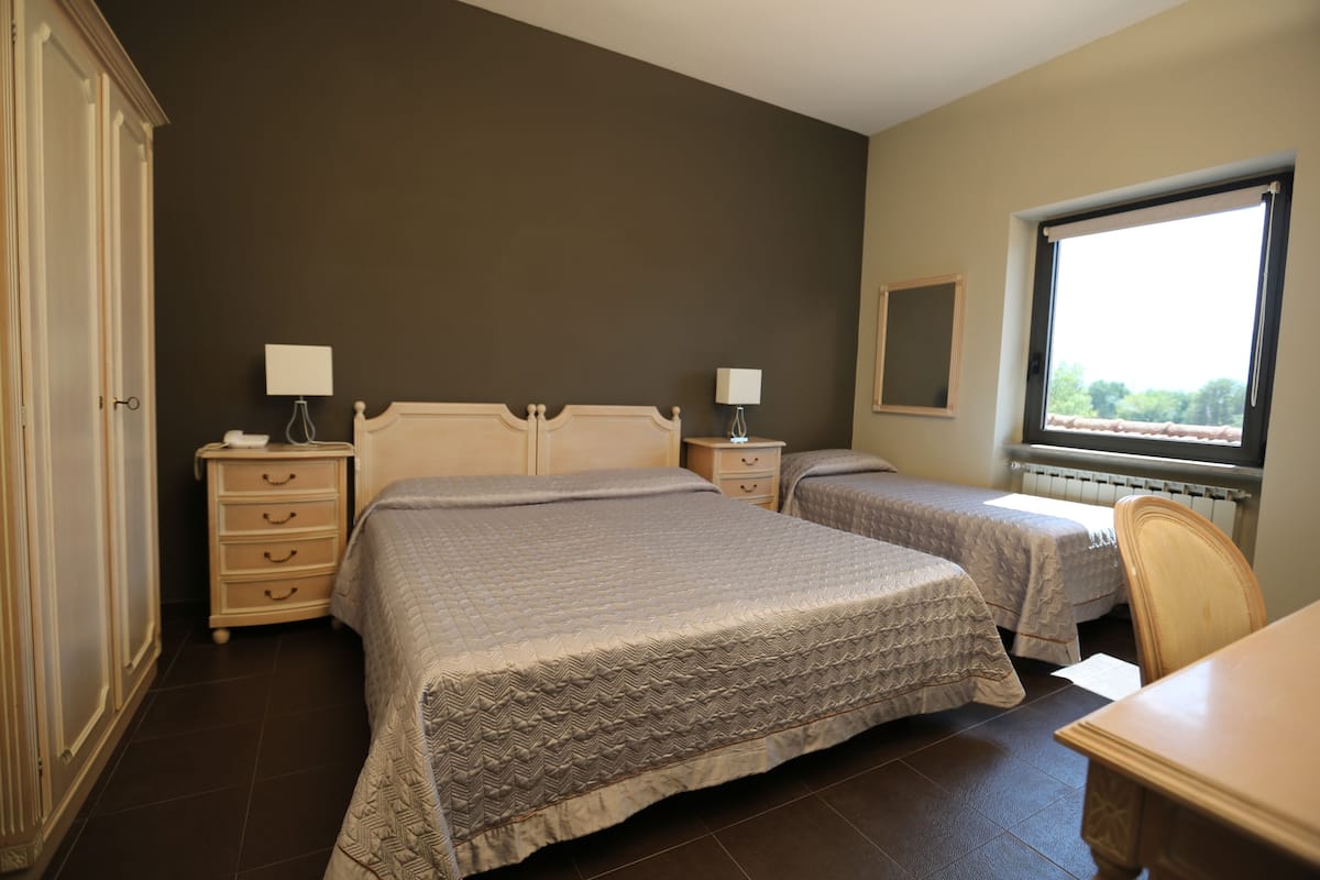 A bedroom with two beds, a dresser, a chair, and a window.