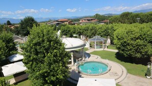 A pool area with a gazebo, surrounded by trees and houses in the background. - Hotel Borgo Antico (Ceprano)