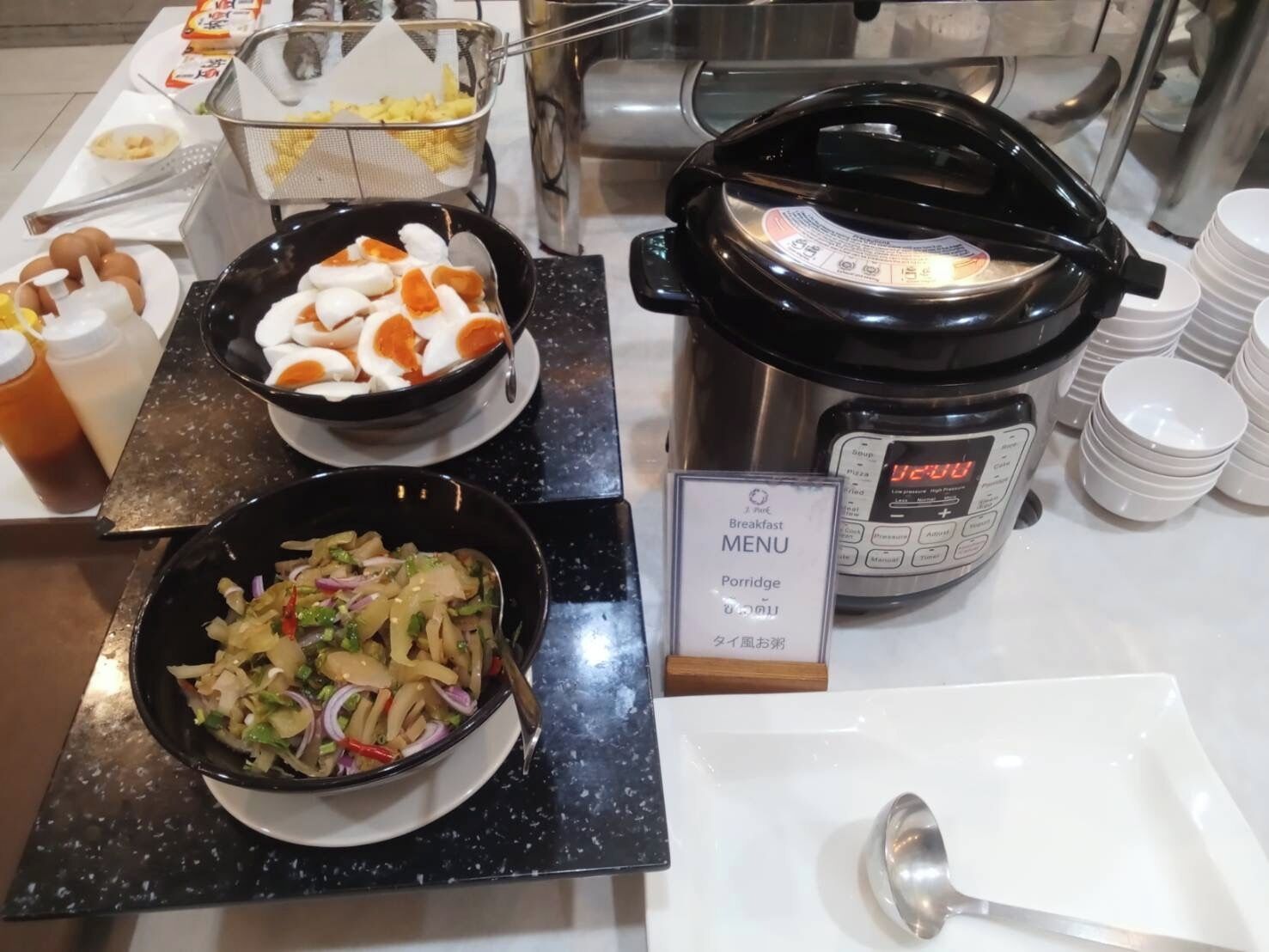 A buffet setup with various dishes, a slow cooker, and a menu sign.
