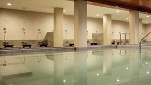 A large indoor swimming pool with multiple lanes, wooden ceiling beams, and a tiled floor. - J Park Hotel (Chonburi)