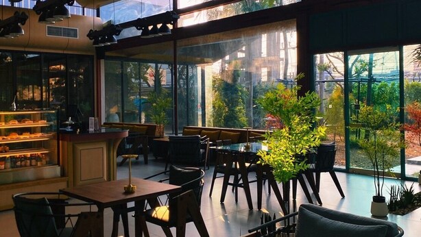 A modern interior with large windows, wooden furniture, and a bar area. - J Park Hotel (Chonburi)