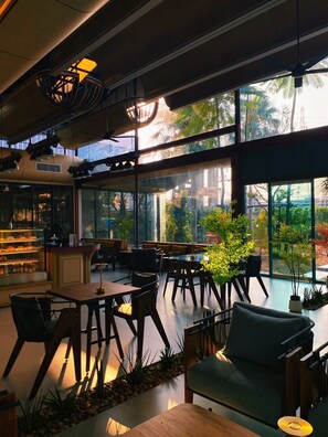 A modern interior with large windows, wooden furniture, and a bar area. - J Park Hotel (Chonburi)