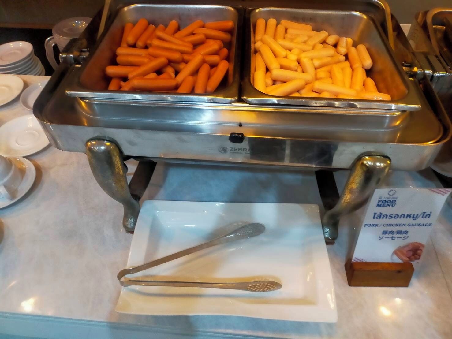 A buffet with trays of carrots and fries, a spoon, and a menu box.