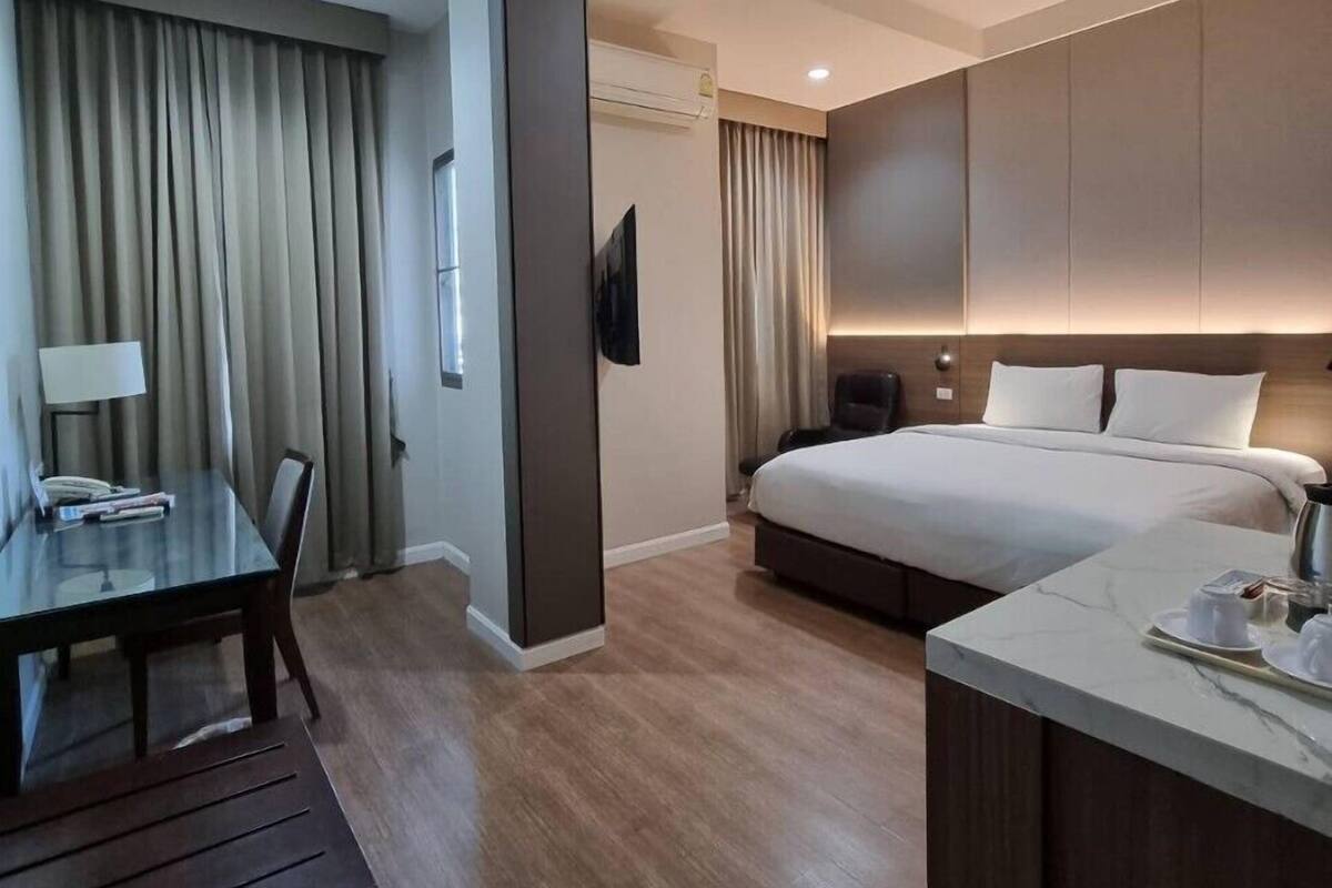 Quarto de hotel moderno com cama, escrivaninha e área de estar.