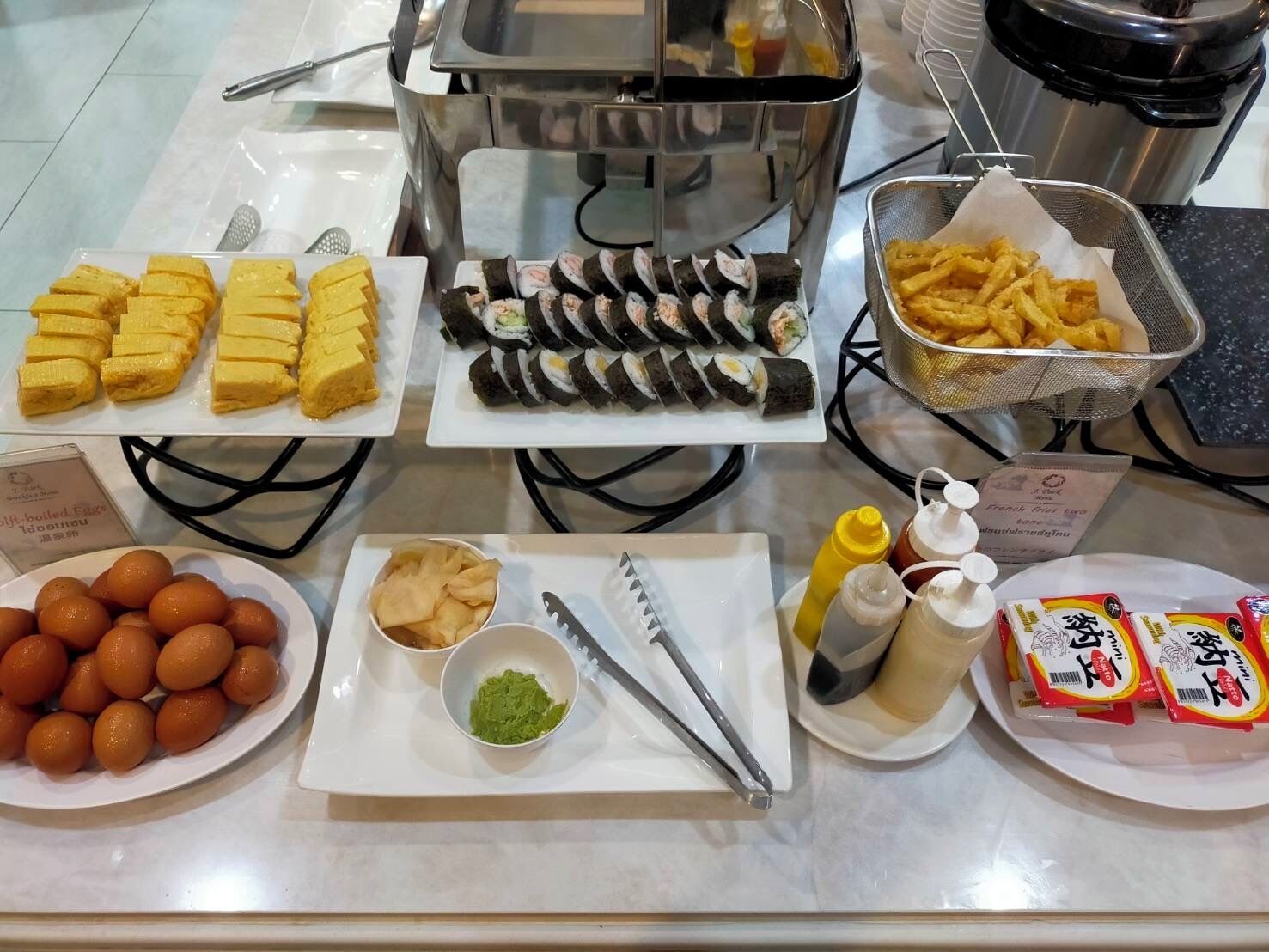 A buffet with various food items including sushi, French fries, and other snacks.