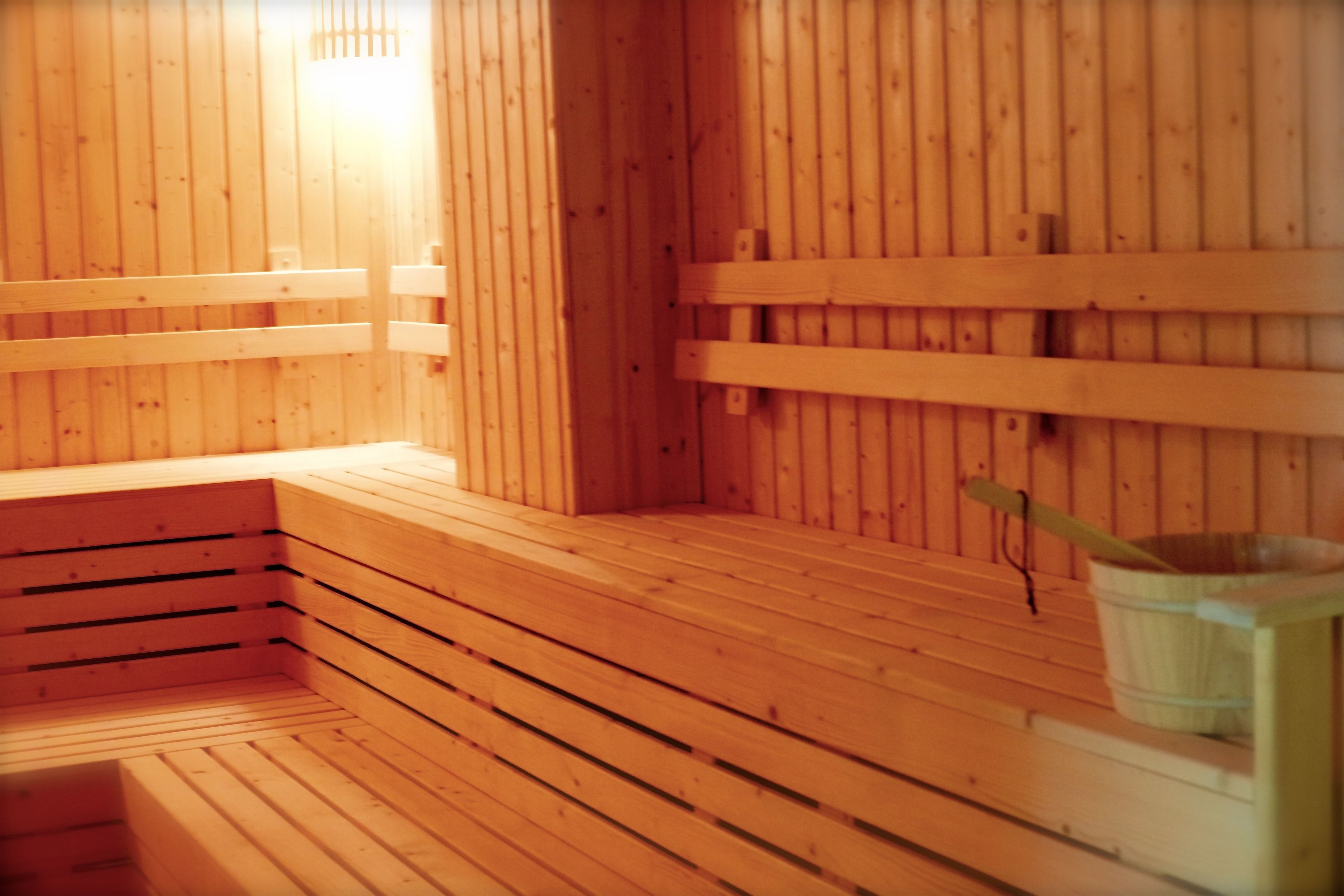 A wooden sauna with benches and a small table with a bowl and a spoon.