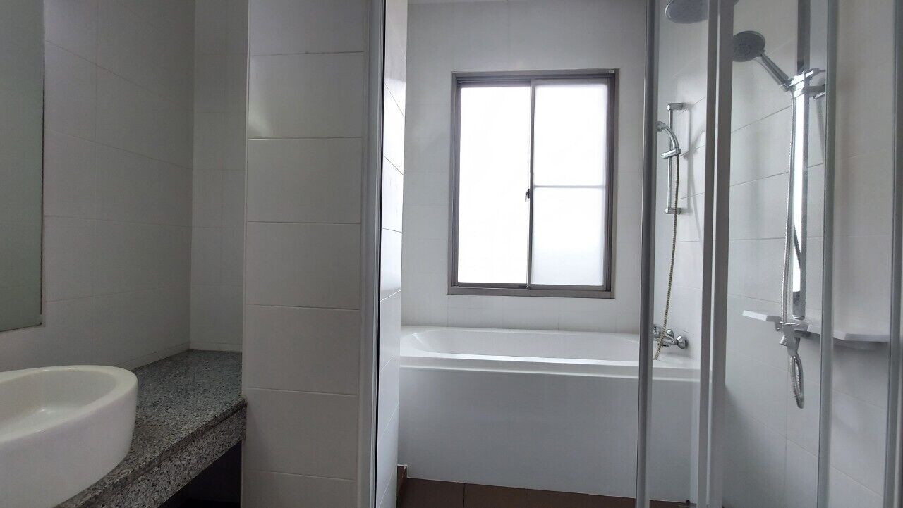 Un baño con una bañera blanca, una ventana y una zona de ducha.