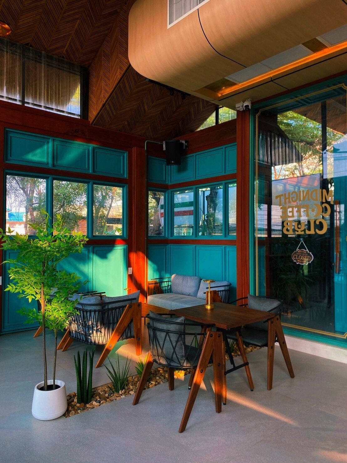 Un intérieur moderne avec de grandes fenêtres, un coin salon avec une table et une plante en pot.