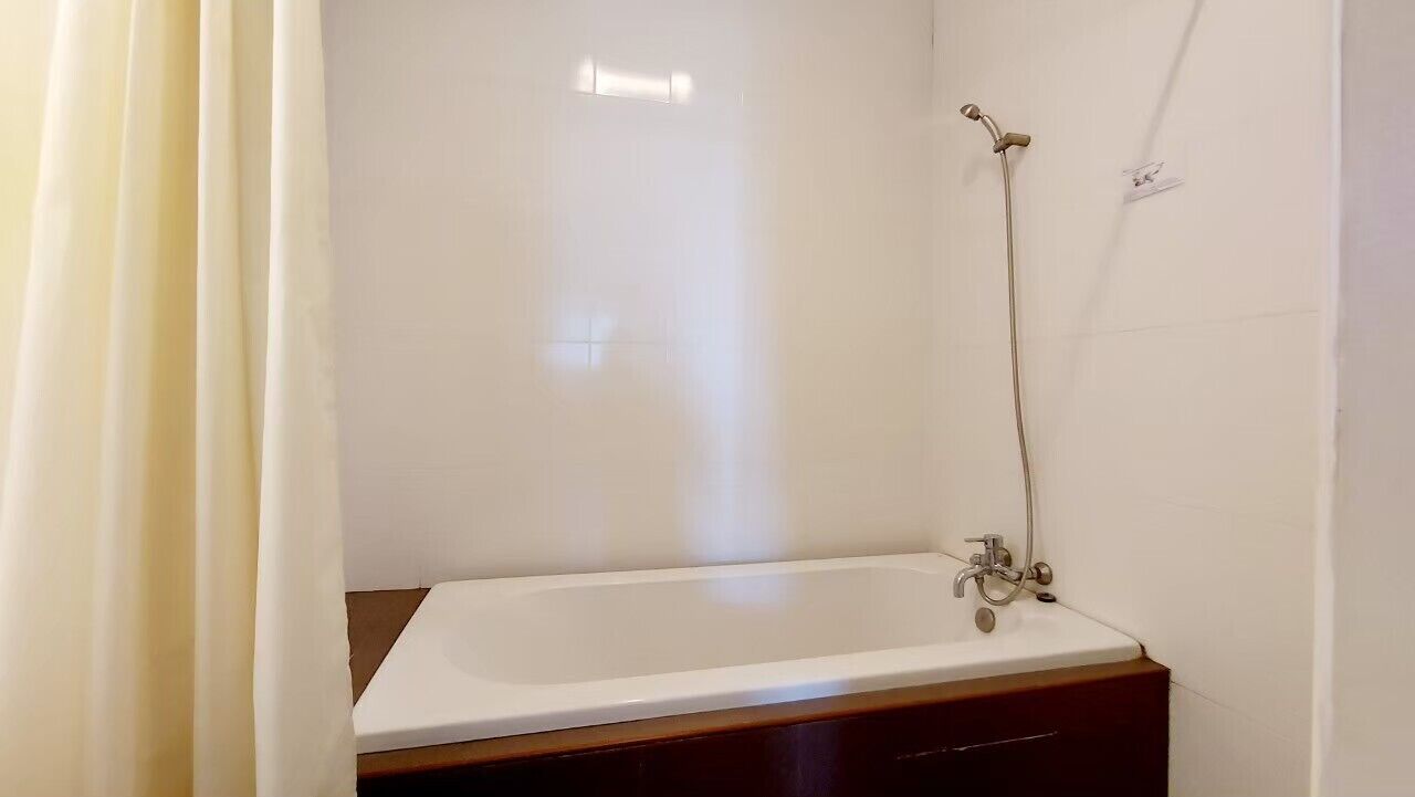 A bathroom with a white bathtub, a shower, and a wooden vanity.